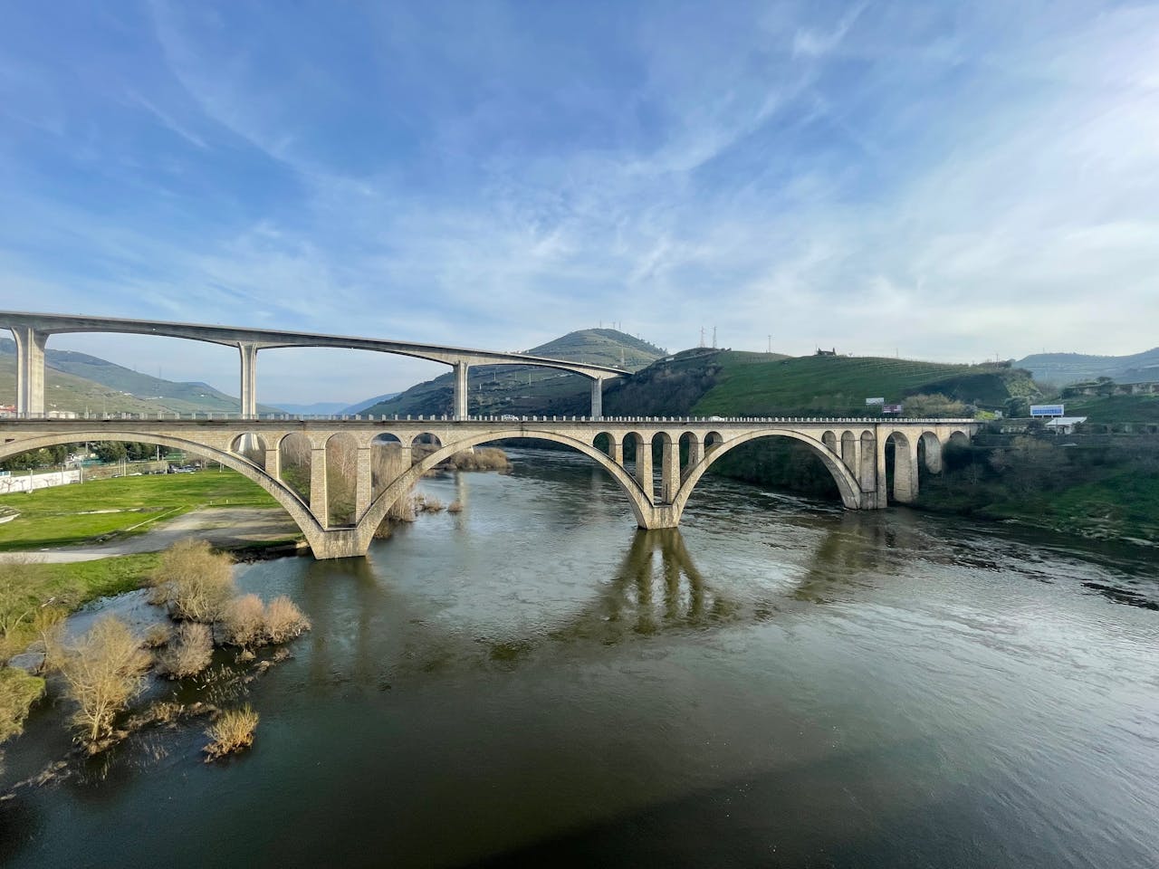 Elegant bridge spanning the Douro River in Peso da Régua, Portugal, under a clear sky.
